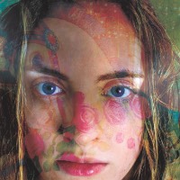 Psychedelic double exposure of a young woman's face looking straight at the camera through a hazy pattern.